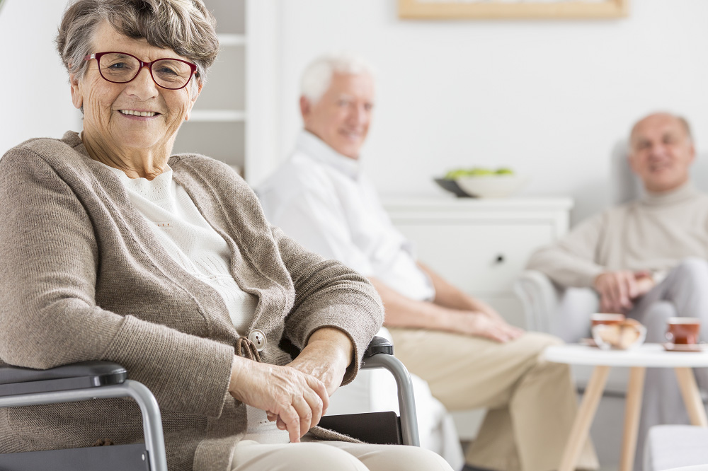 An older, smiling woman is sitting in an armchair